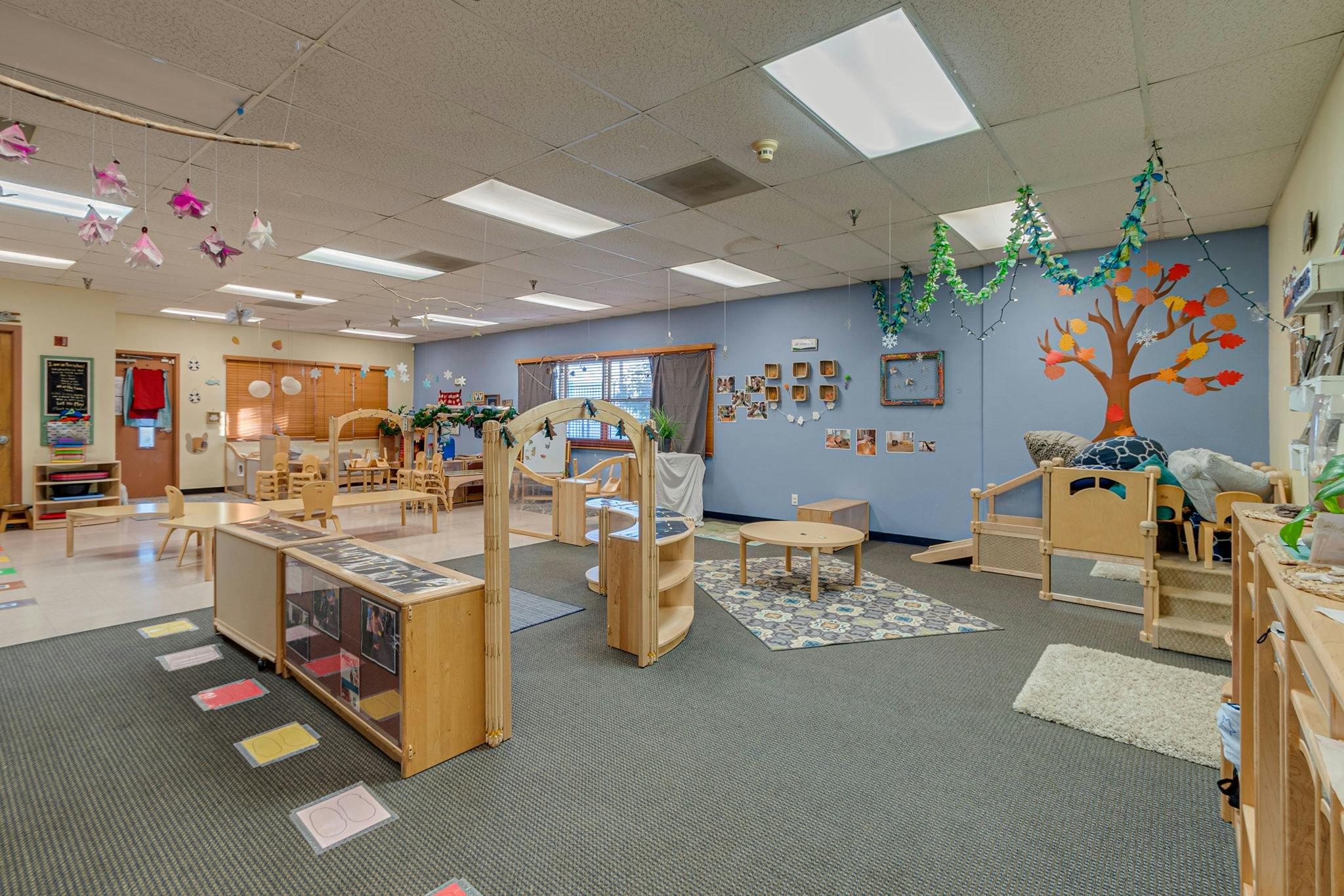 Empty classroom with small tables, chairs, and learning materials