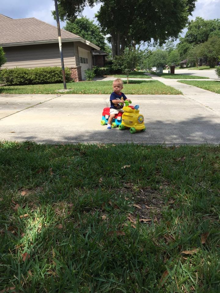 Child on a toy ride-on train on a sidewalk