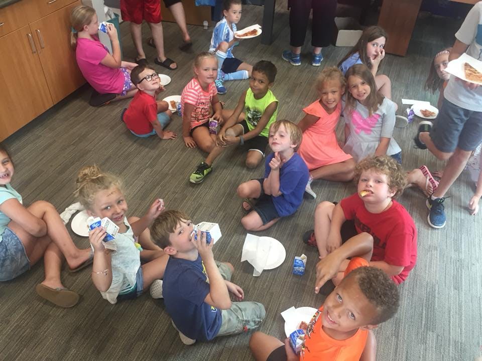 Group of children sitting on the floor eating and drinking