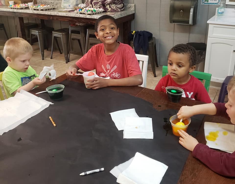 Children sitting at a table with cups and paper