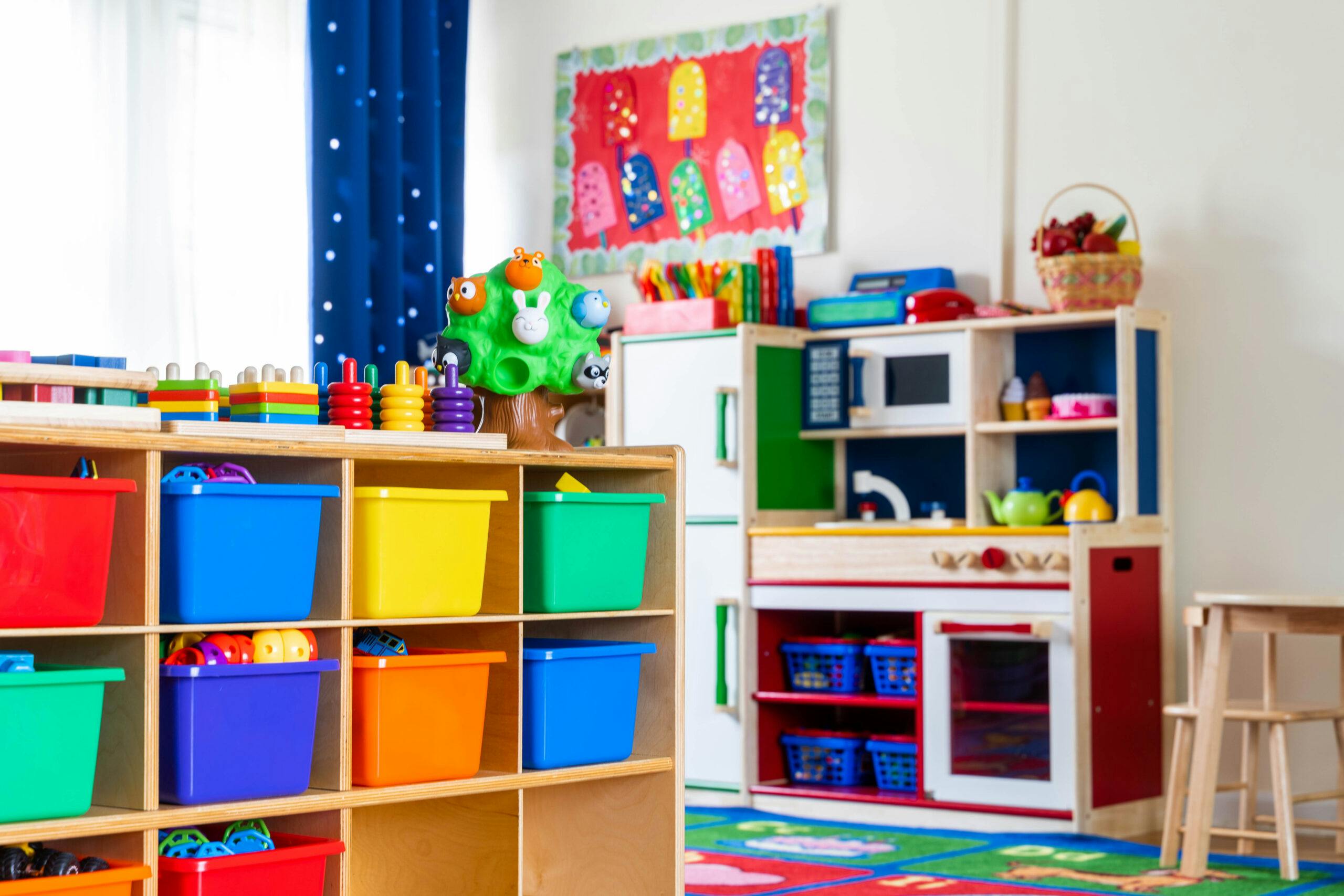 children's playroom with cubbies of toys, a play kitchen, and a tree toy
