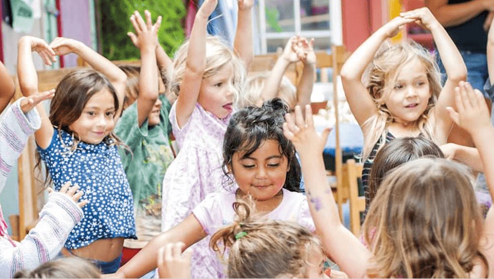 Group of children with hands raised