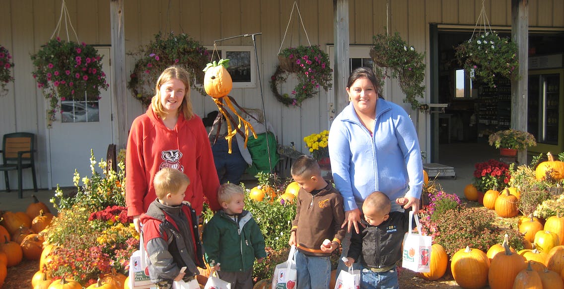 Two people and four children standing among pumpkins and plants