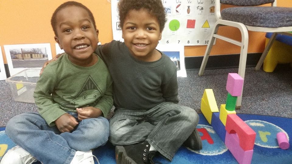 Two children sitting on the floor with building blocks