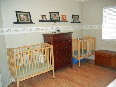 Two cribs and a dresser in a room
