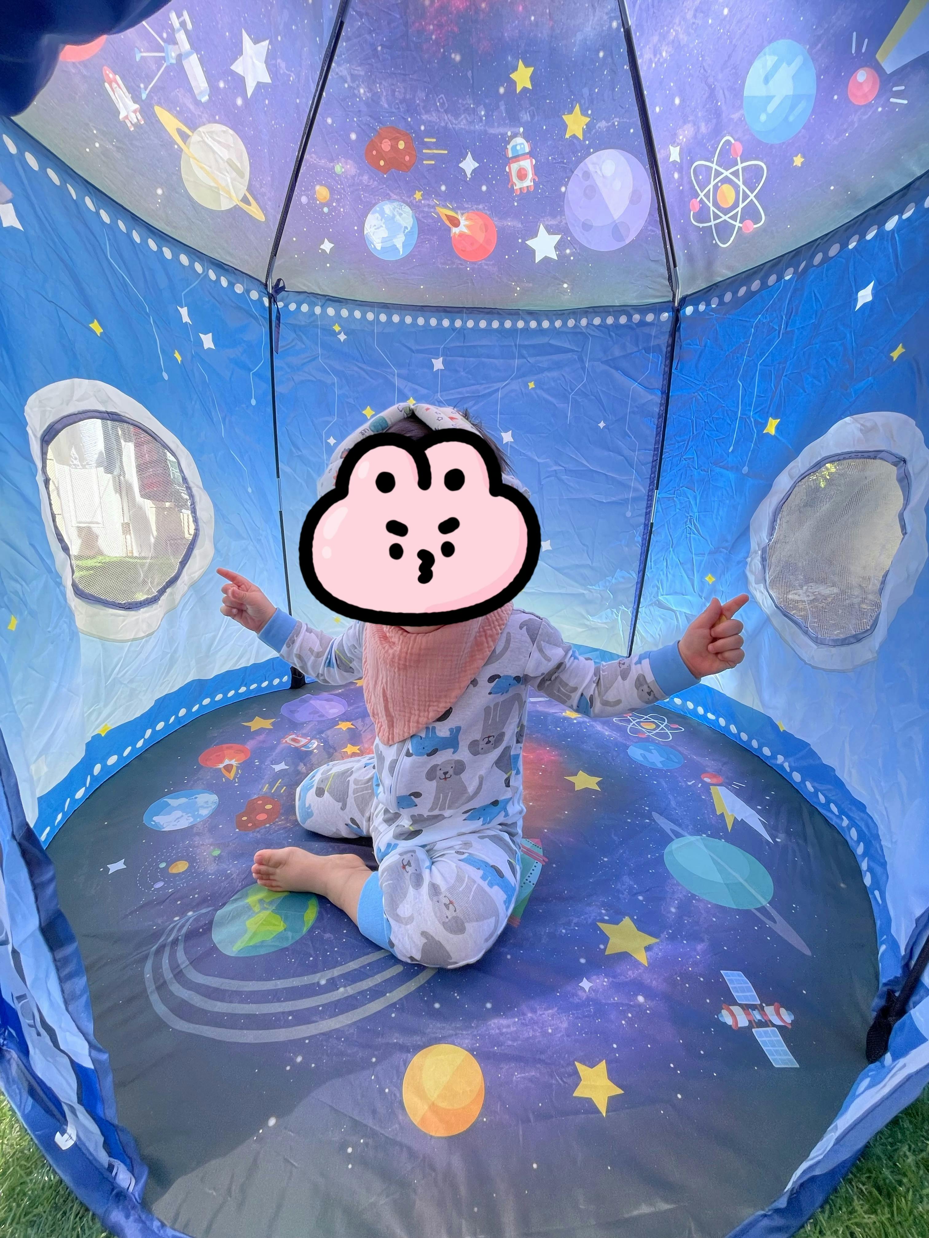 Child sitting in a space-themed play tent