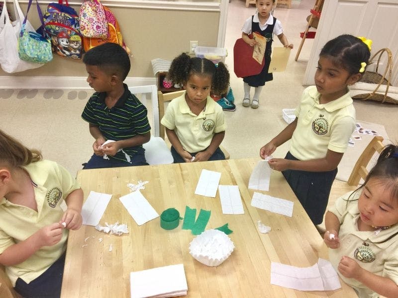 Children at a table doing an art activity with paper and green shapes
