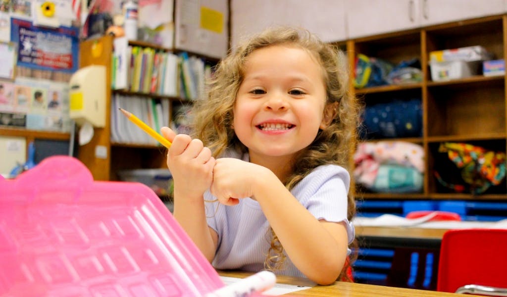 Child holding a pencil in a classroom