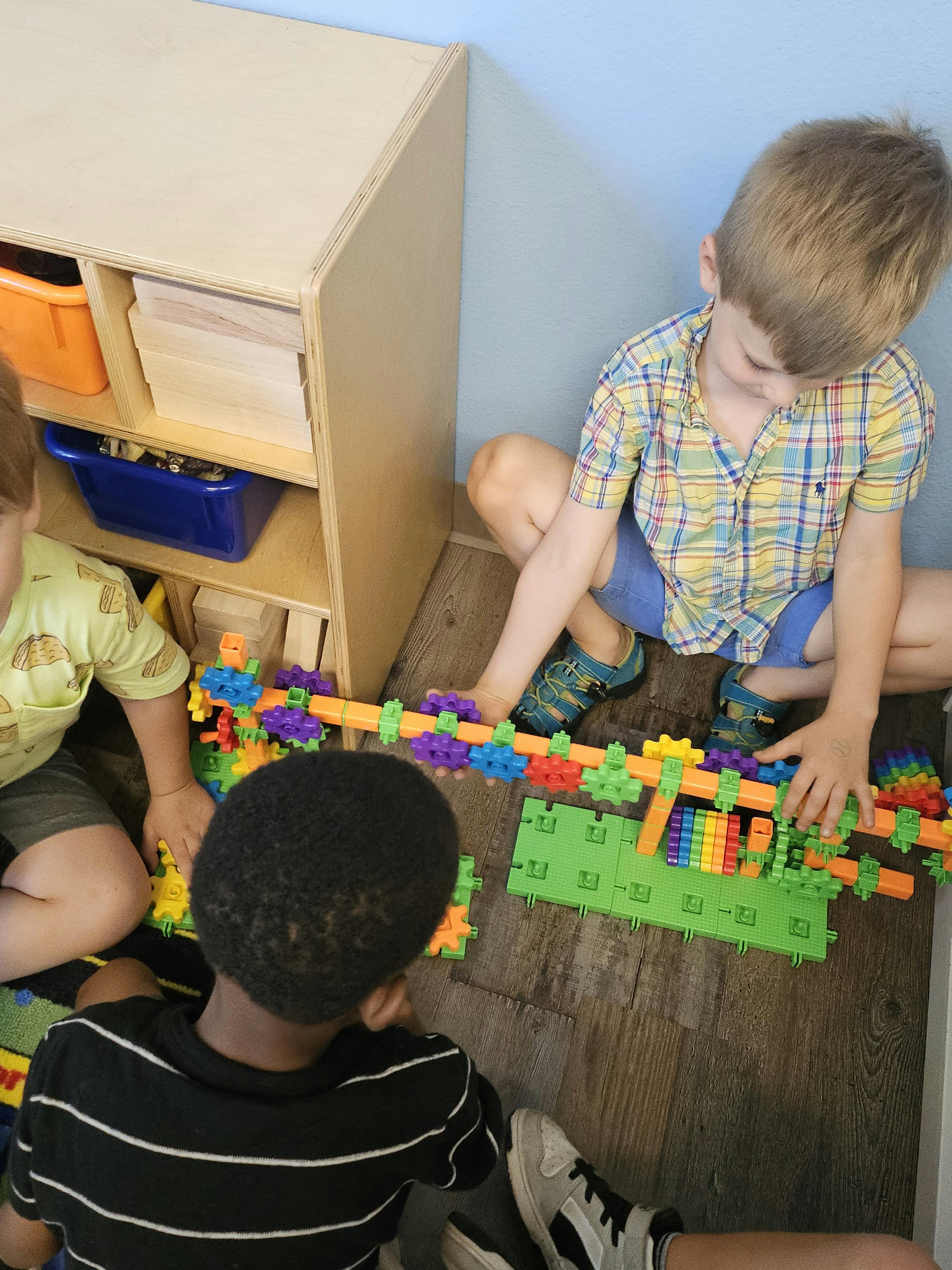 Three children playing with colorful building blocks on the floor
