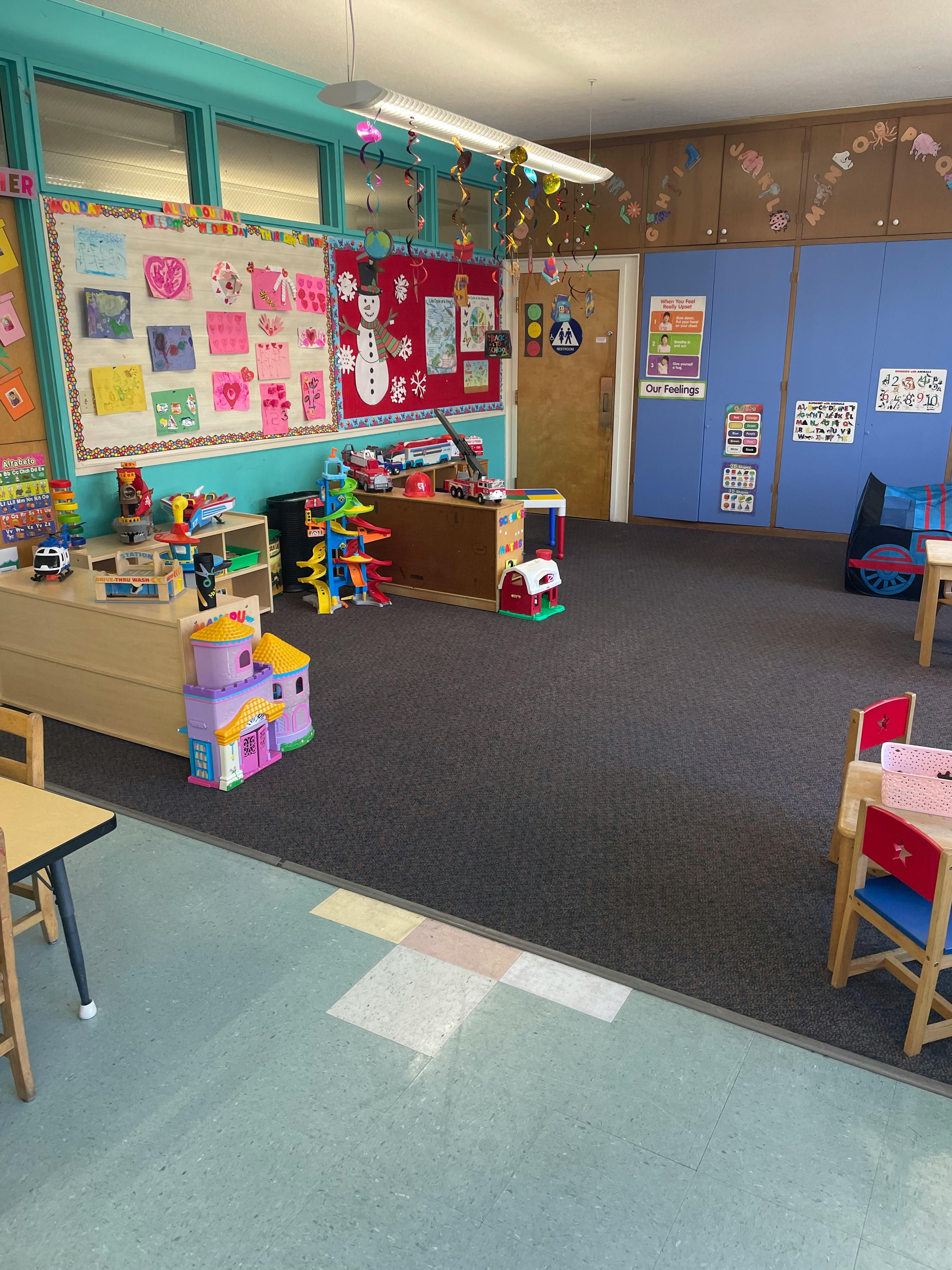 Empty classroom with toys, bulletin boards, and small tables
