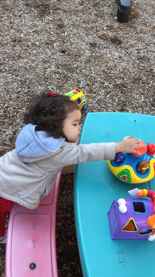 Child playing with colorful toys on a blue table