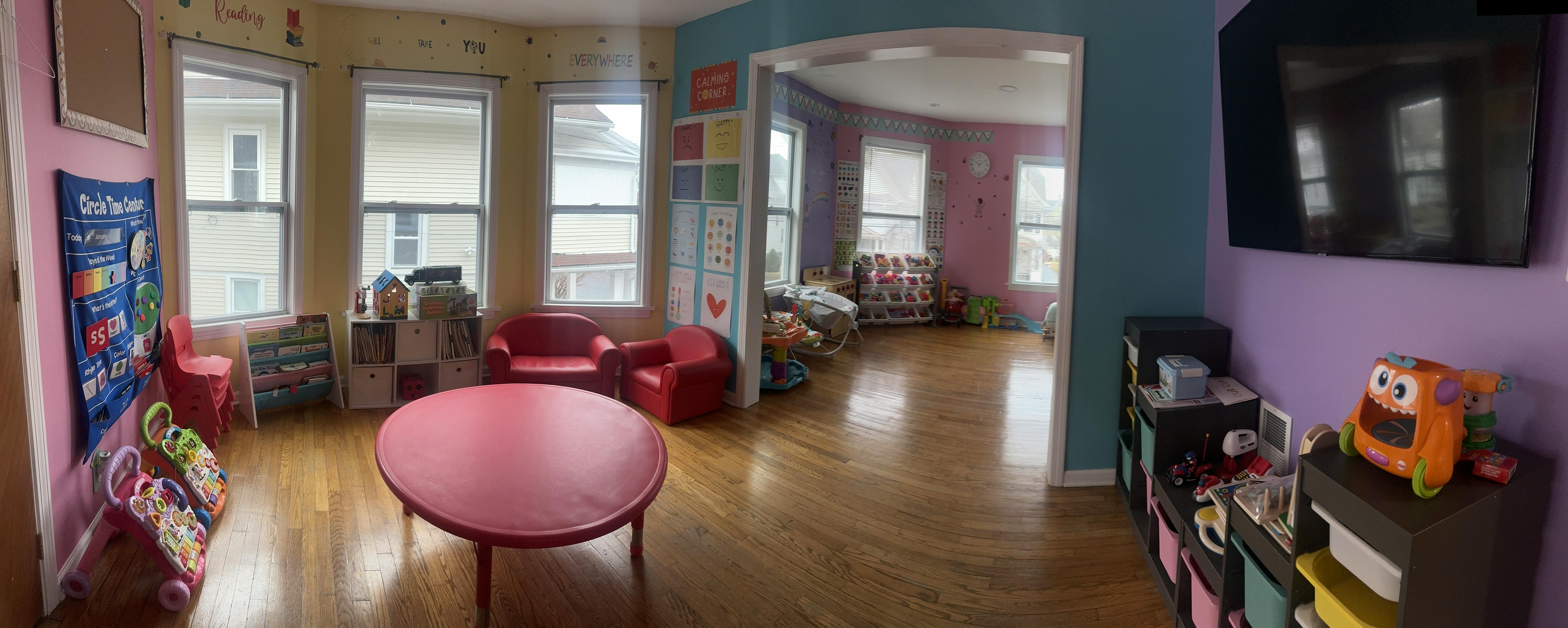 Playroom with small red table and chairs, toys, and windows