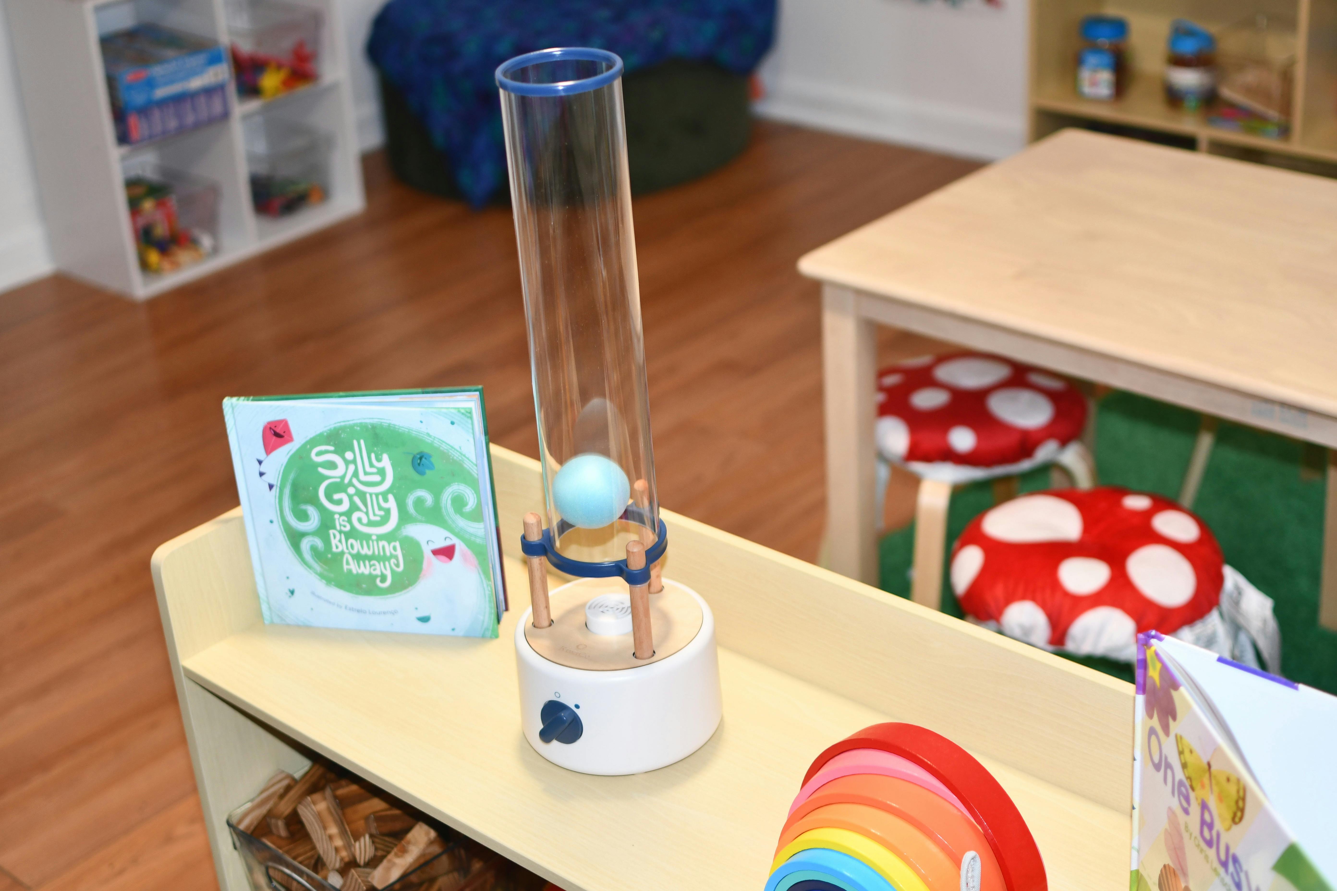 Science toy with a ball in a tube next to a book in a classroom