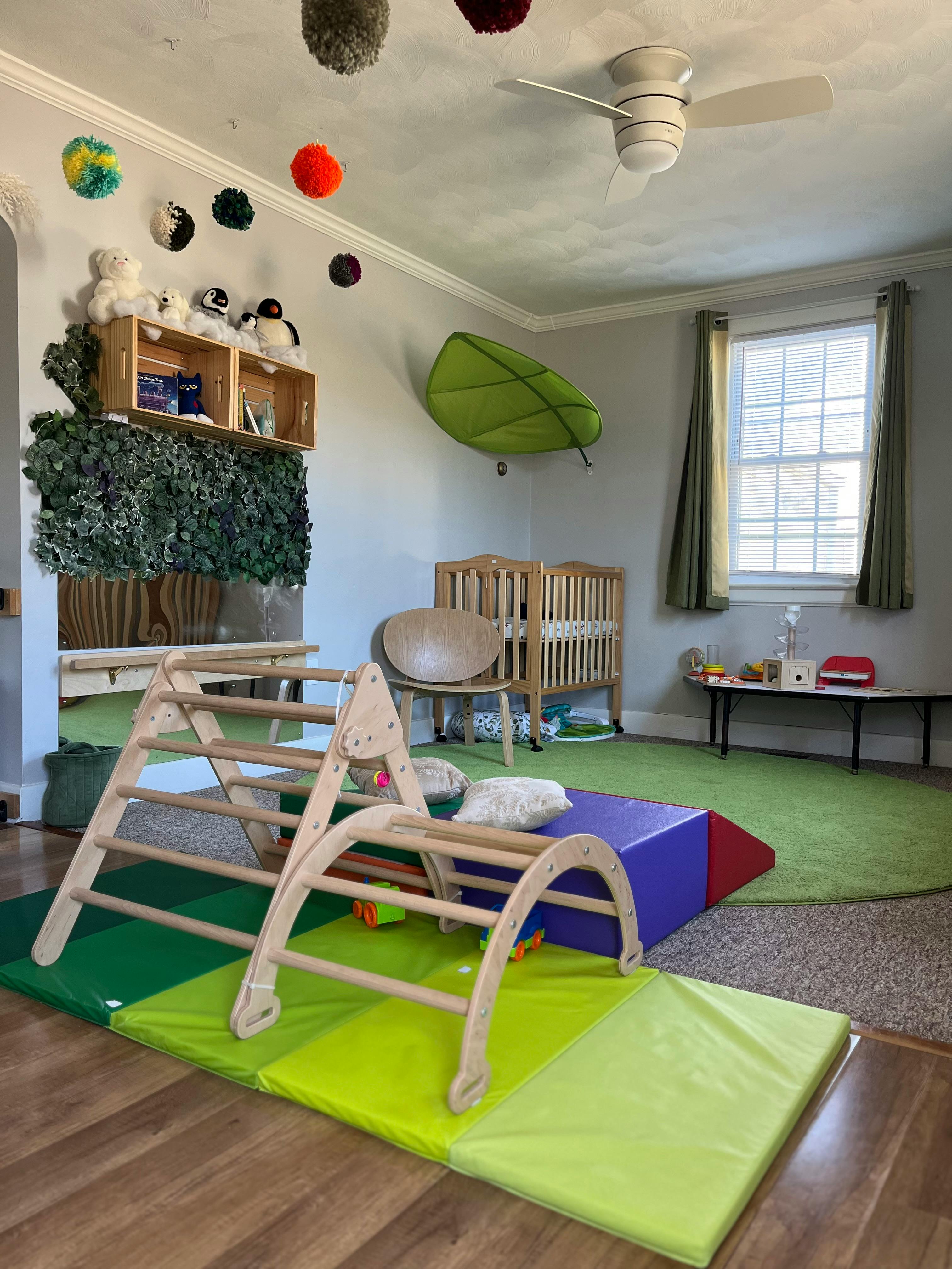 Indoor play area with wooden climbing structures on green mats