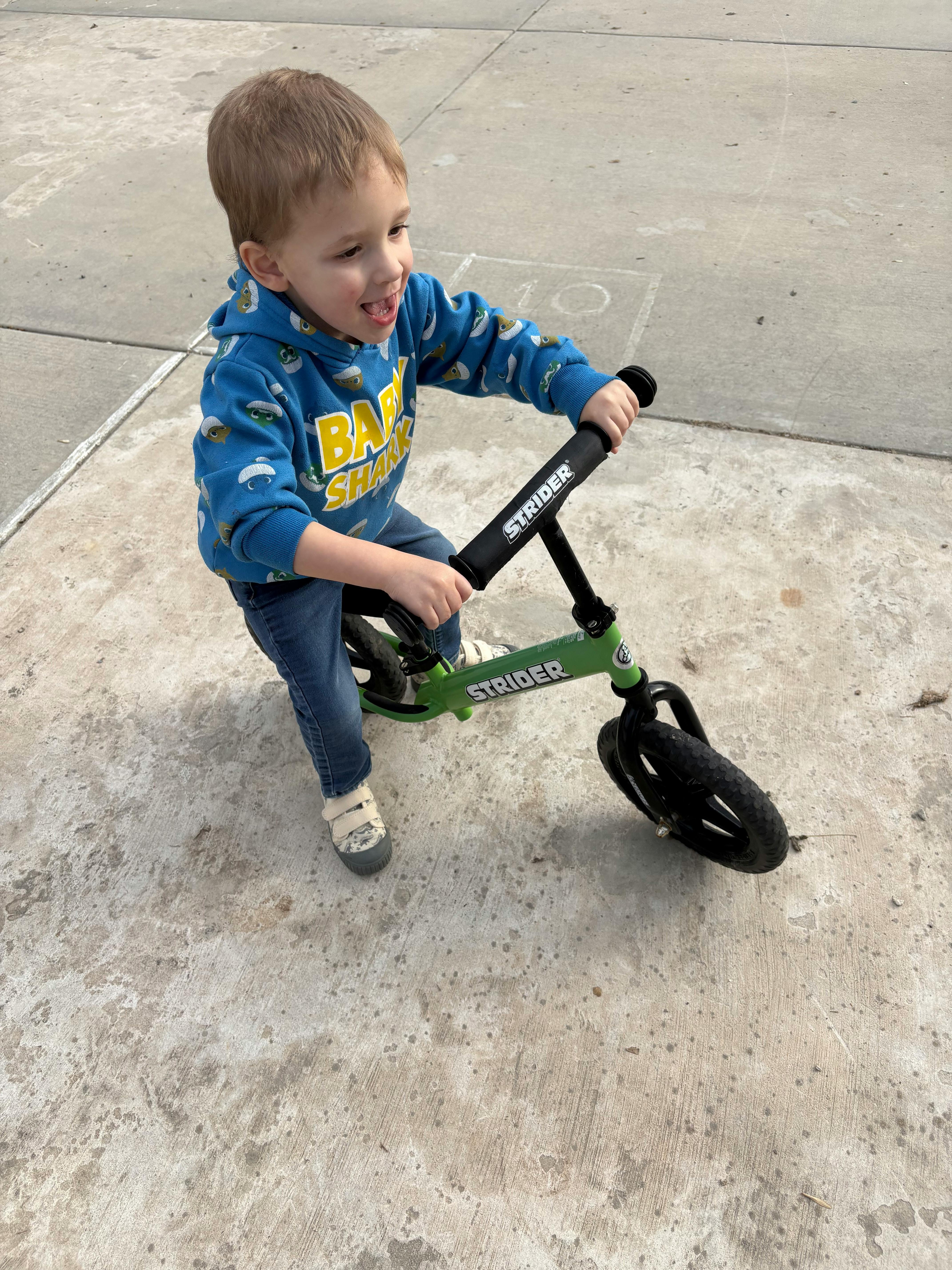 Child on a green balance bike