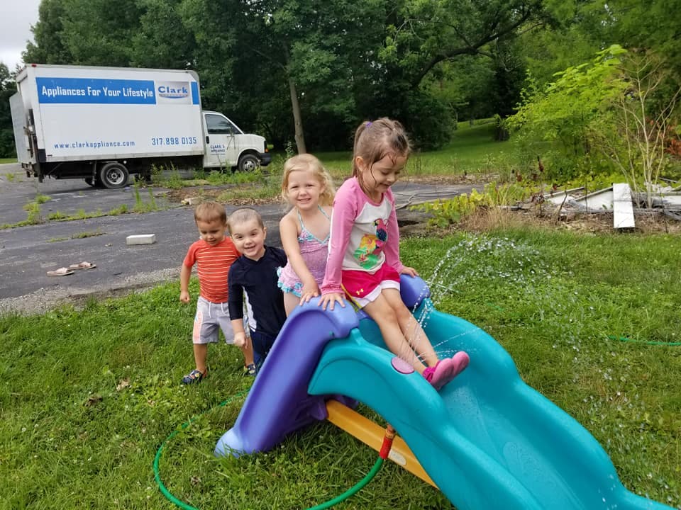 Children playing on a water slide in a grassy area