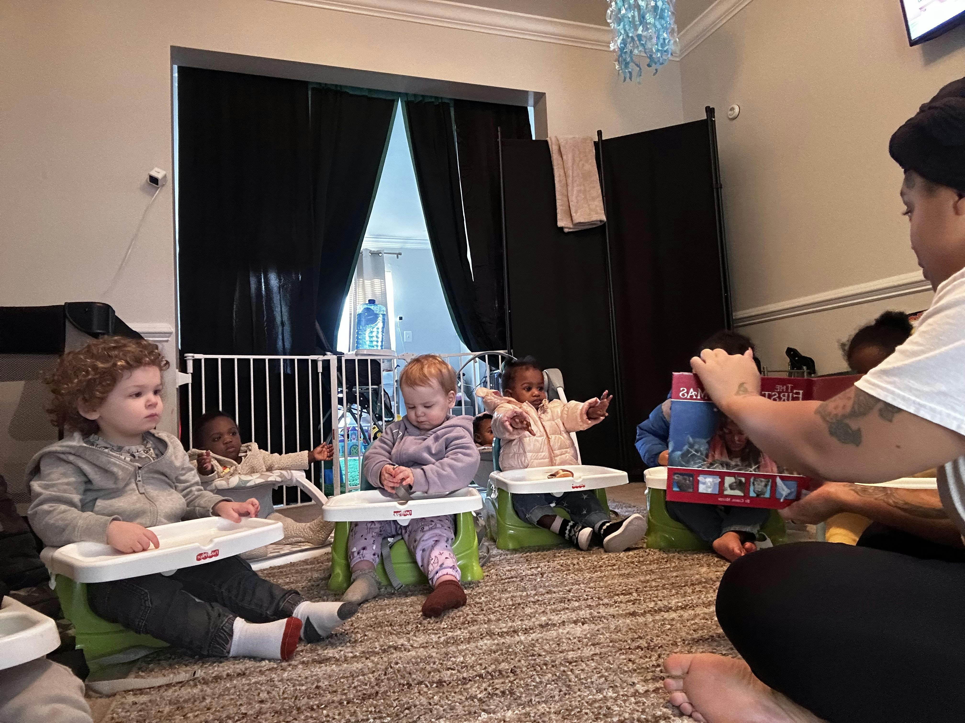 Adult interacting with multiple children seated in high chairs