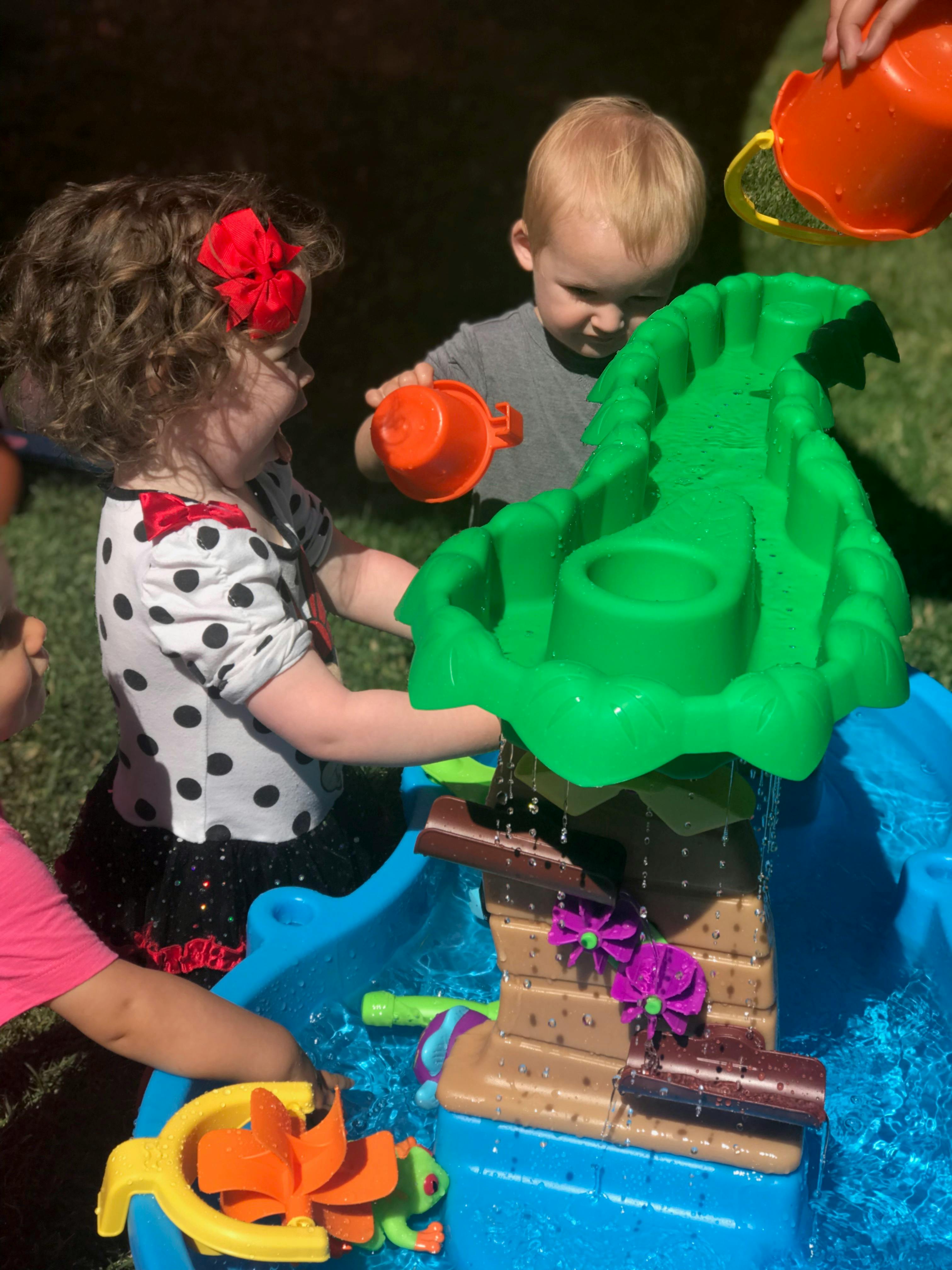 Two children playing with a water table toy