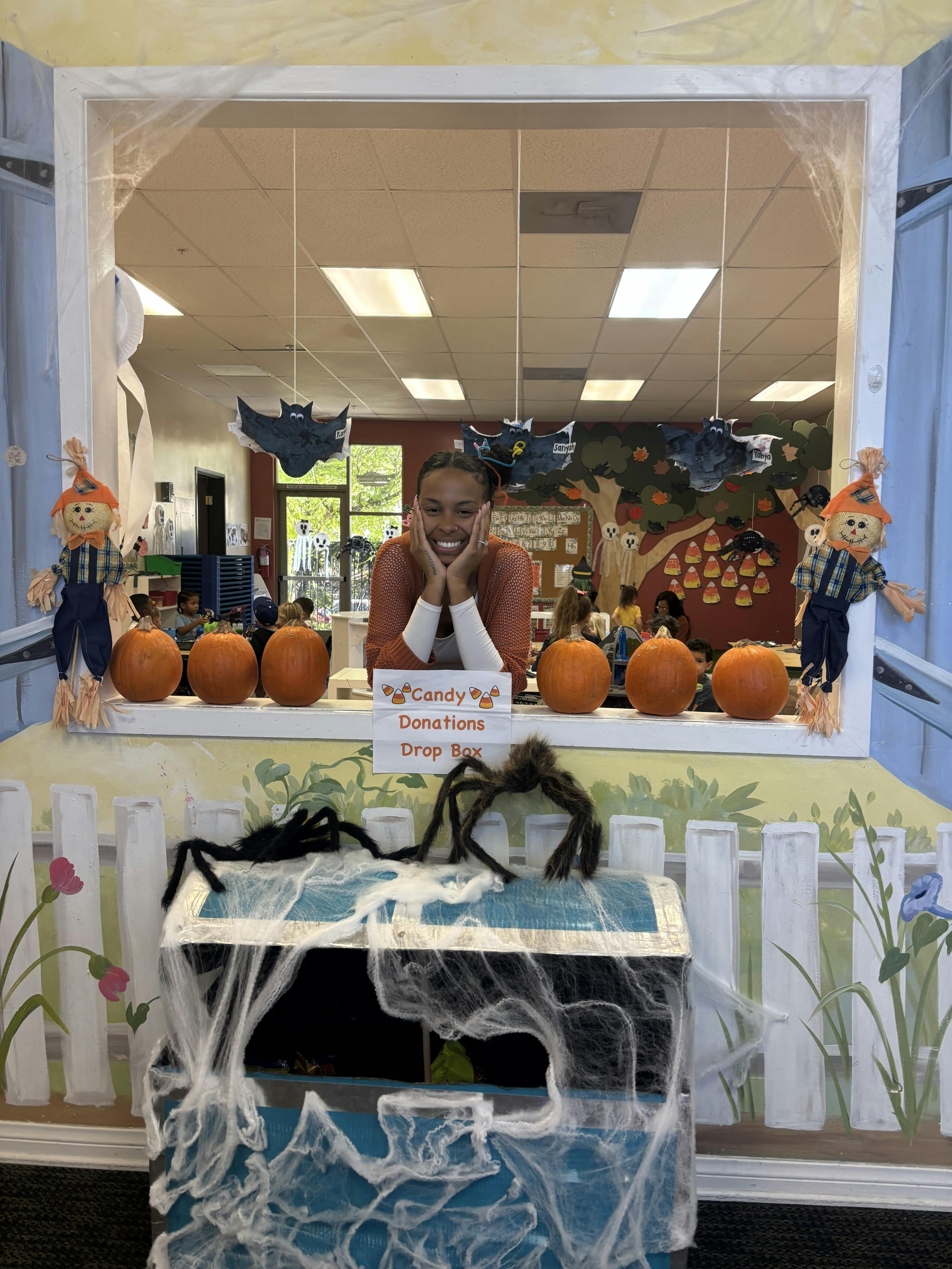 Person leaning over a candy donations drop box in a decorated classroom