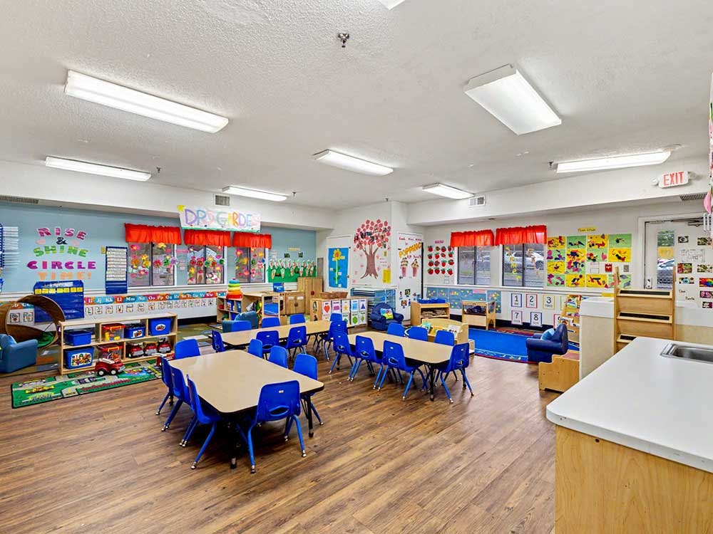Classroom with small tables and chairs, toys, and art on the walls