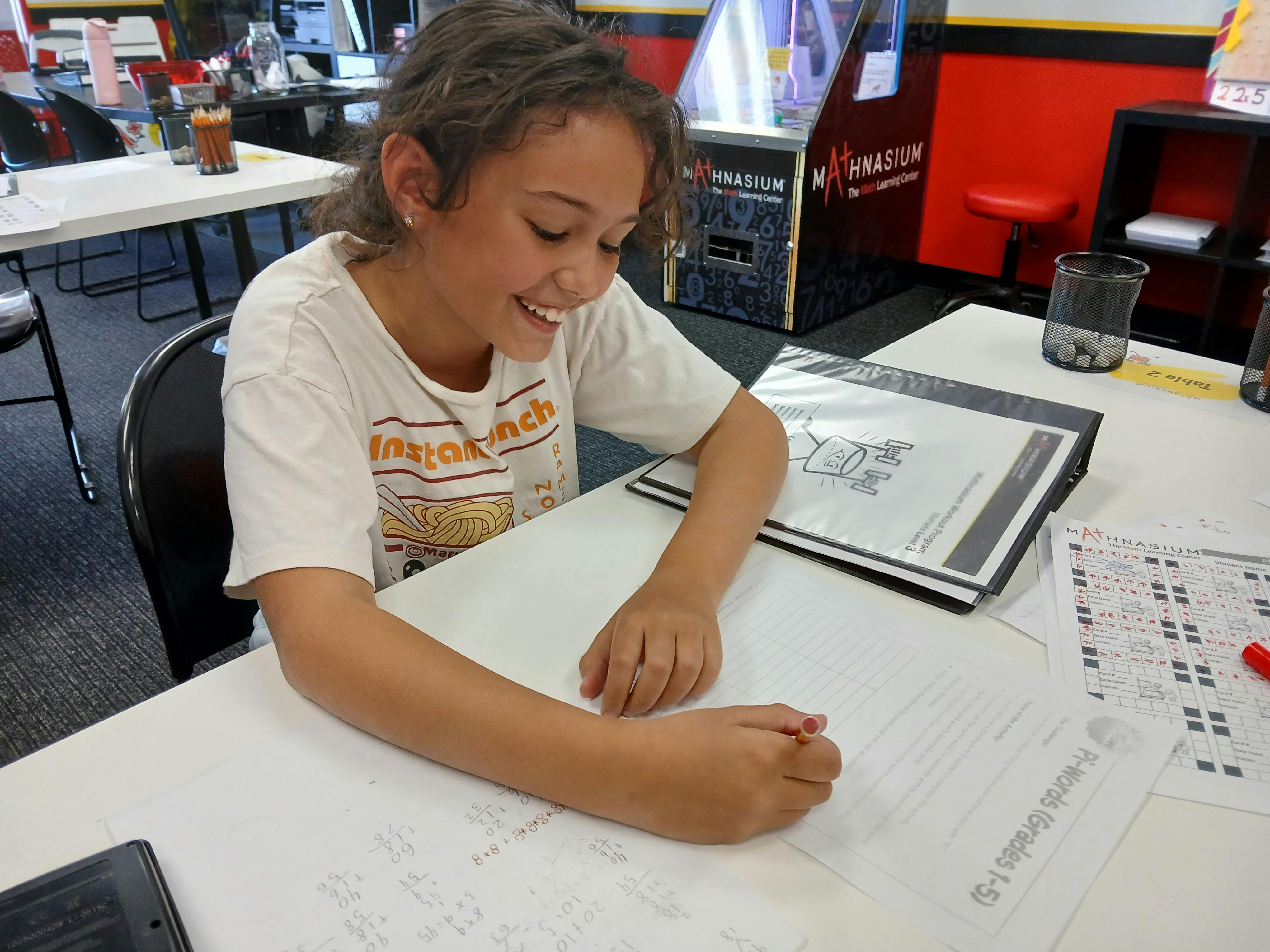 Child writing at a desk with papers and a binder