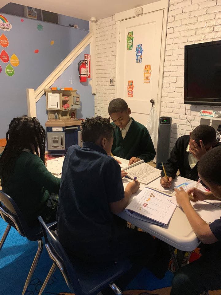 Four children studying at a table in a classroom