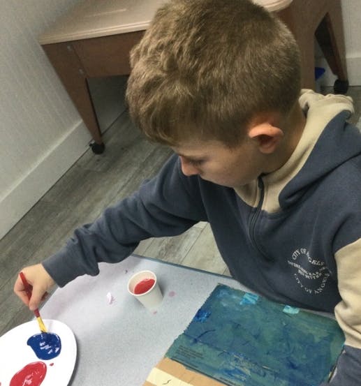 Child painting with red and blue paint
