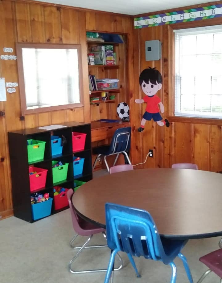 Classroom with wooden walls, round table, chairs, and storage cubbies