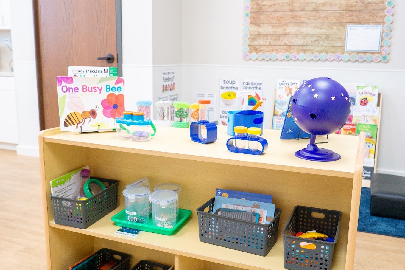 Educational toys and books arranged on a wooden classroom shelf