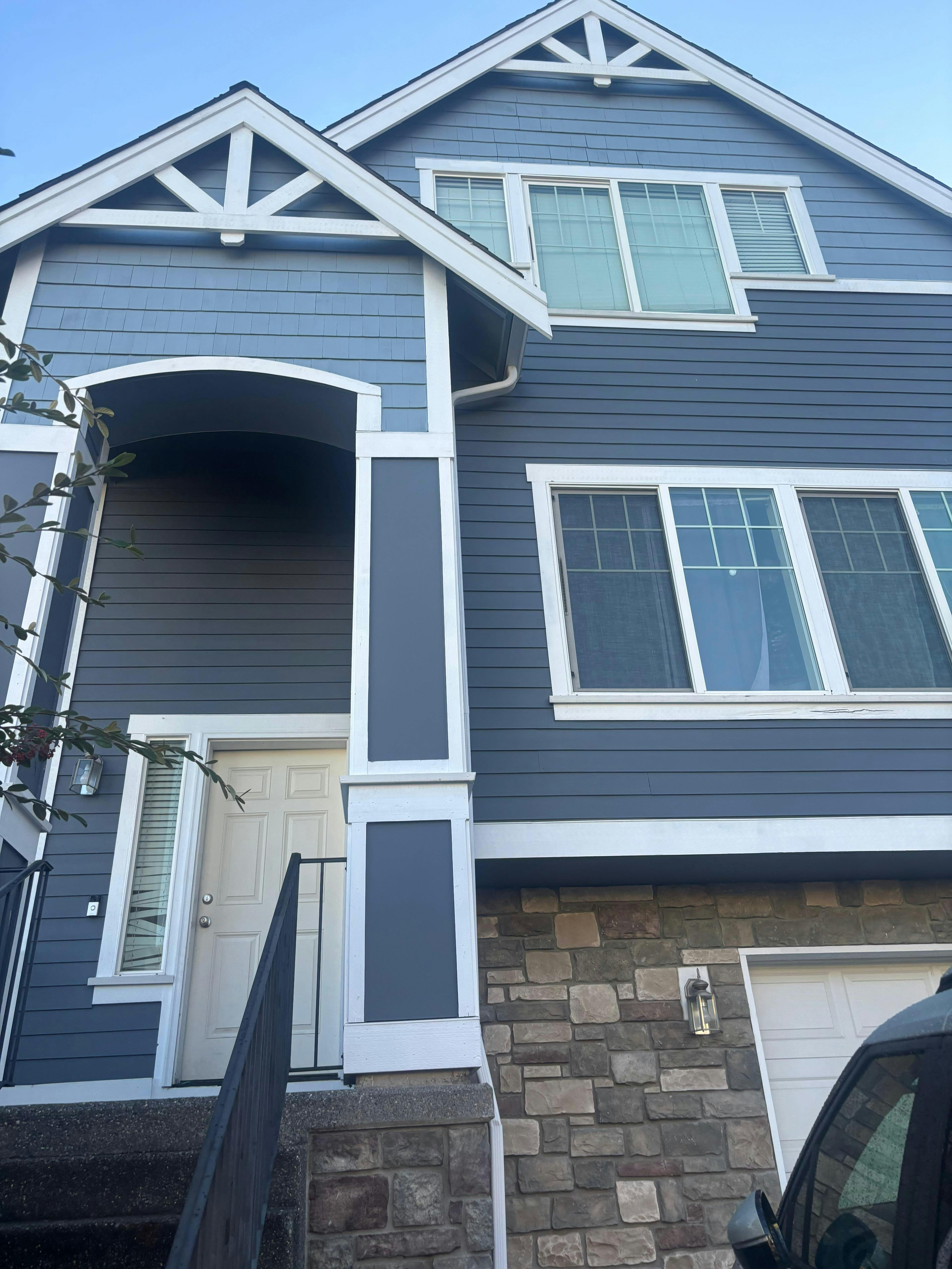 Front exterior of a multi-story building with blue siding and stone facade