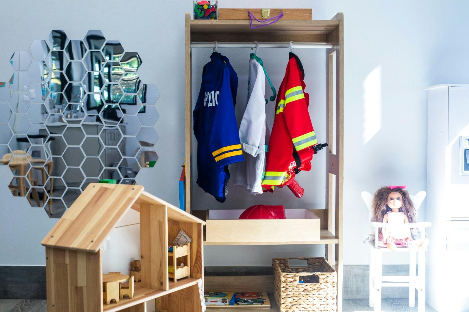 Dress-up clothes hanging in a wardrobe next to a dollhouse