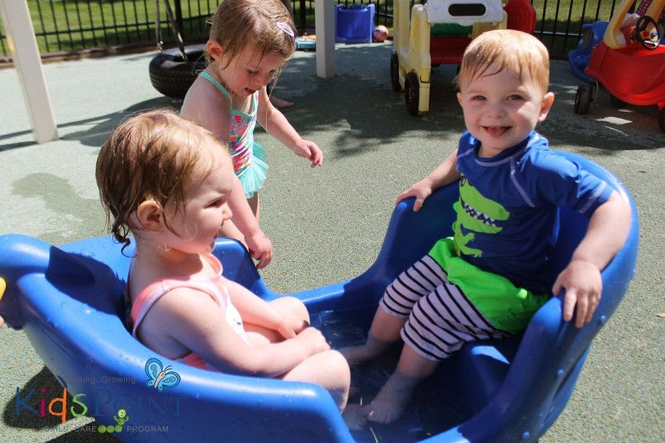 Three children playing in a blue water table