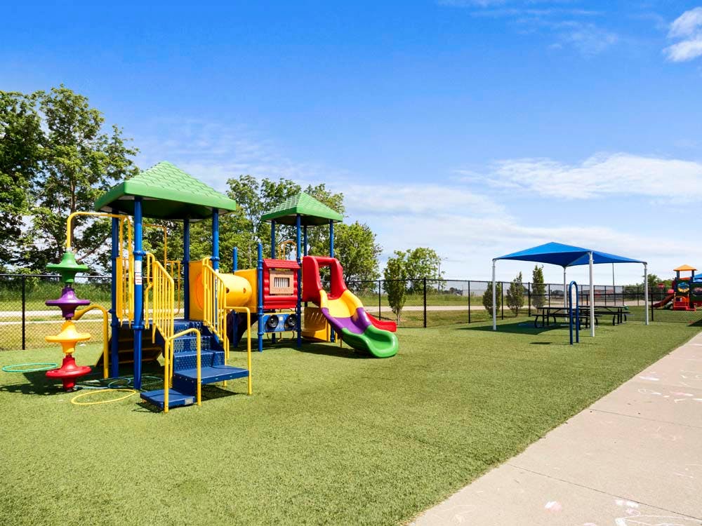 Colorful outdoor playground with slides, stairs, and a covered picnic area