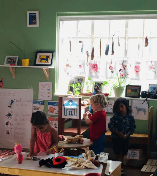 Three children playing in a classroom
