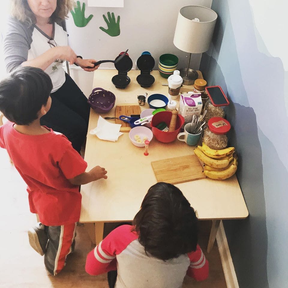 Adult and two children at a table with cooking ingredients and baking supplies