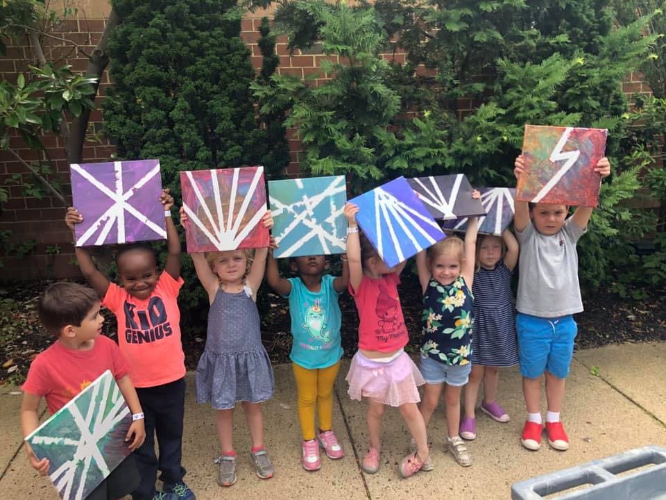 Group of children holding up painted canvases