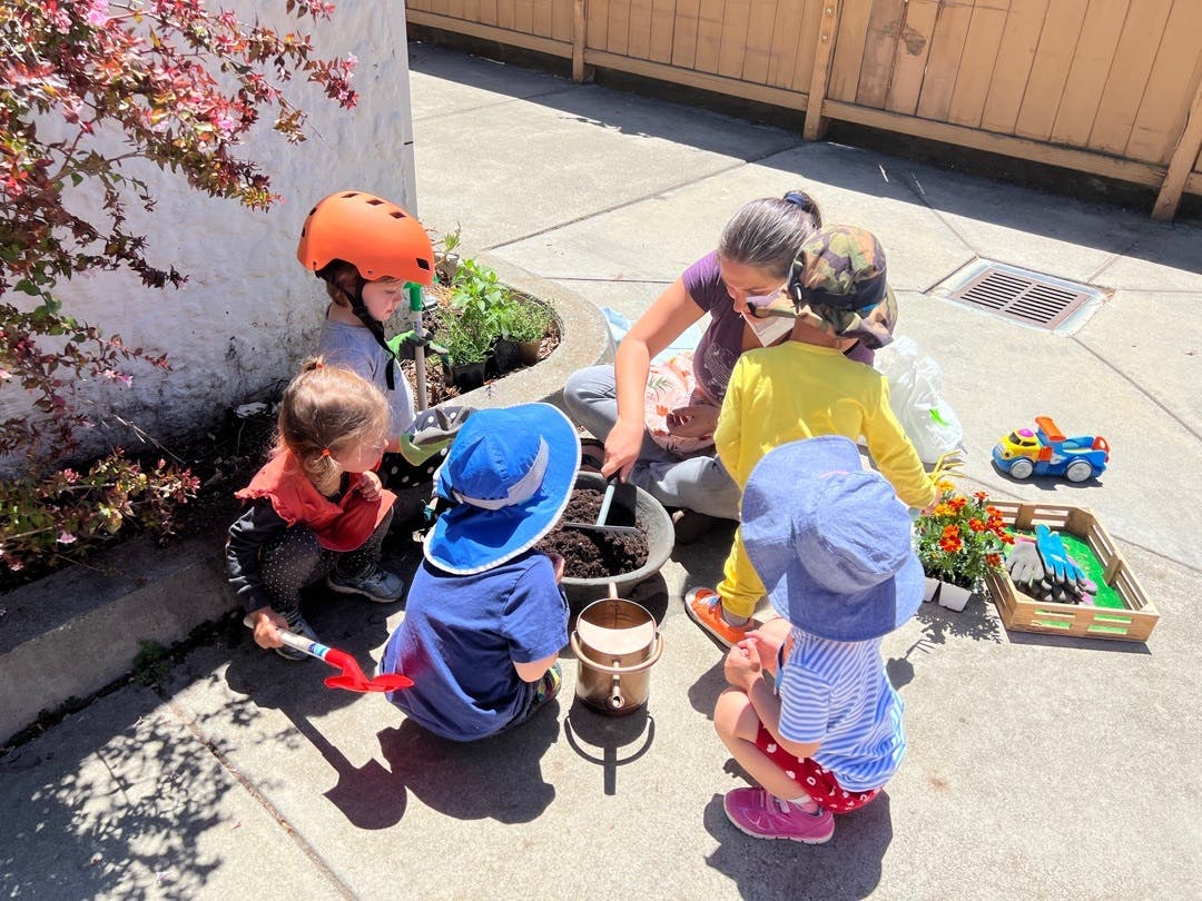 Adult and children planting in a pot outdoors