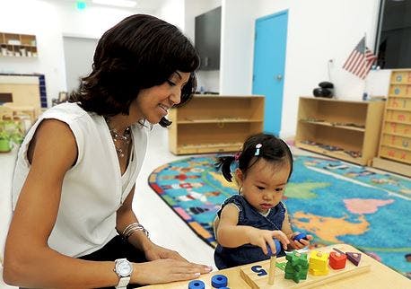 Person and child playing with colorful blocks in a classroom