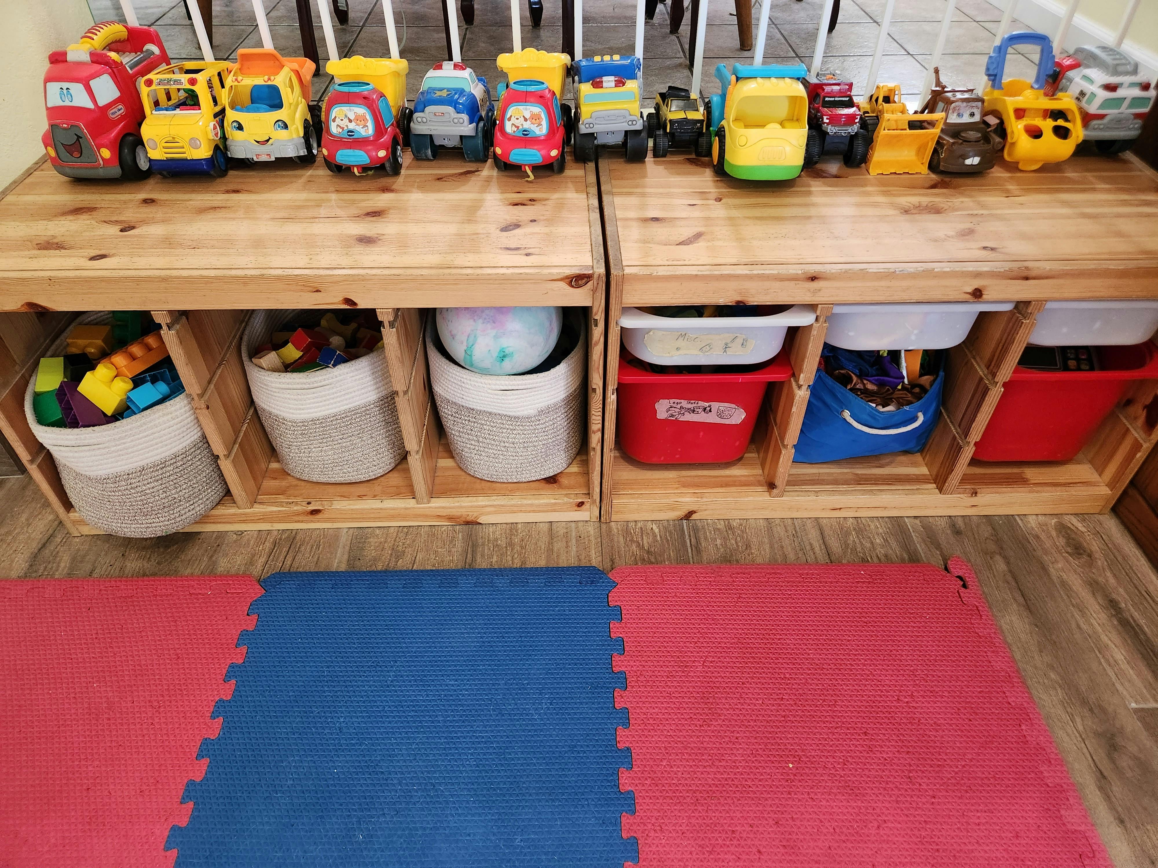 Toy trucks on wooden shelves with storage bins below
