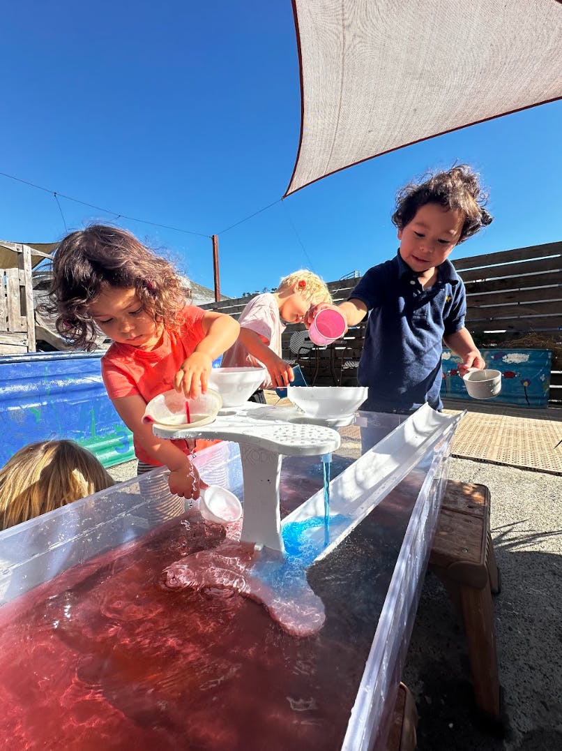 Children playing with water and toys in an outdoor water table