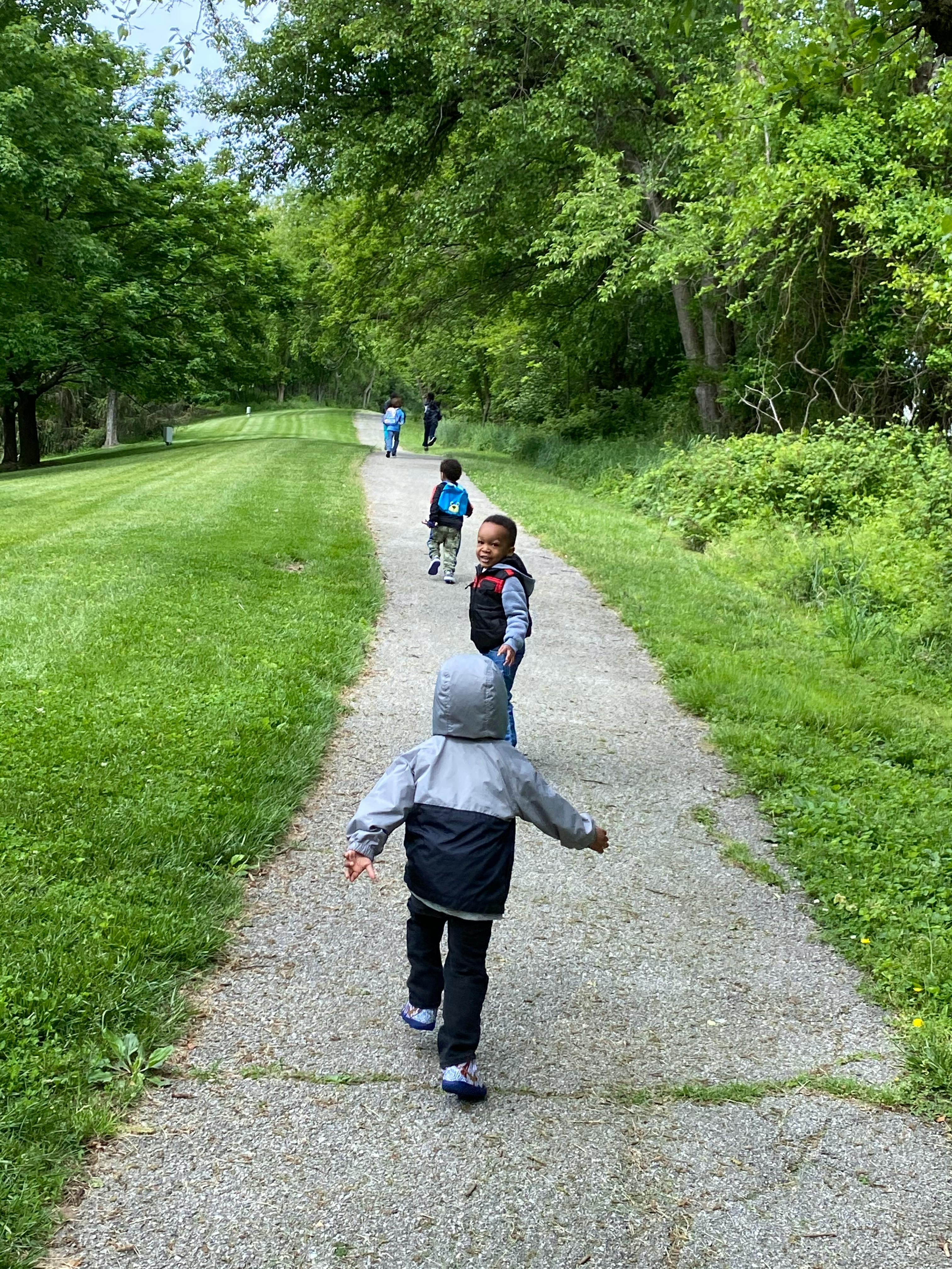 Children walking on a path with trees and grass