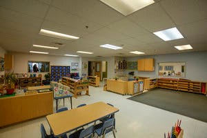 Empty classroom with tables, chairs, and shelves