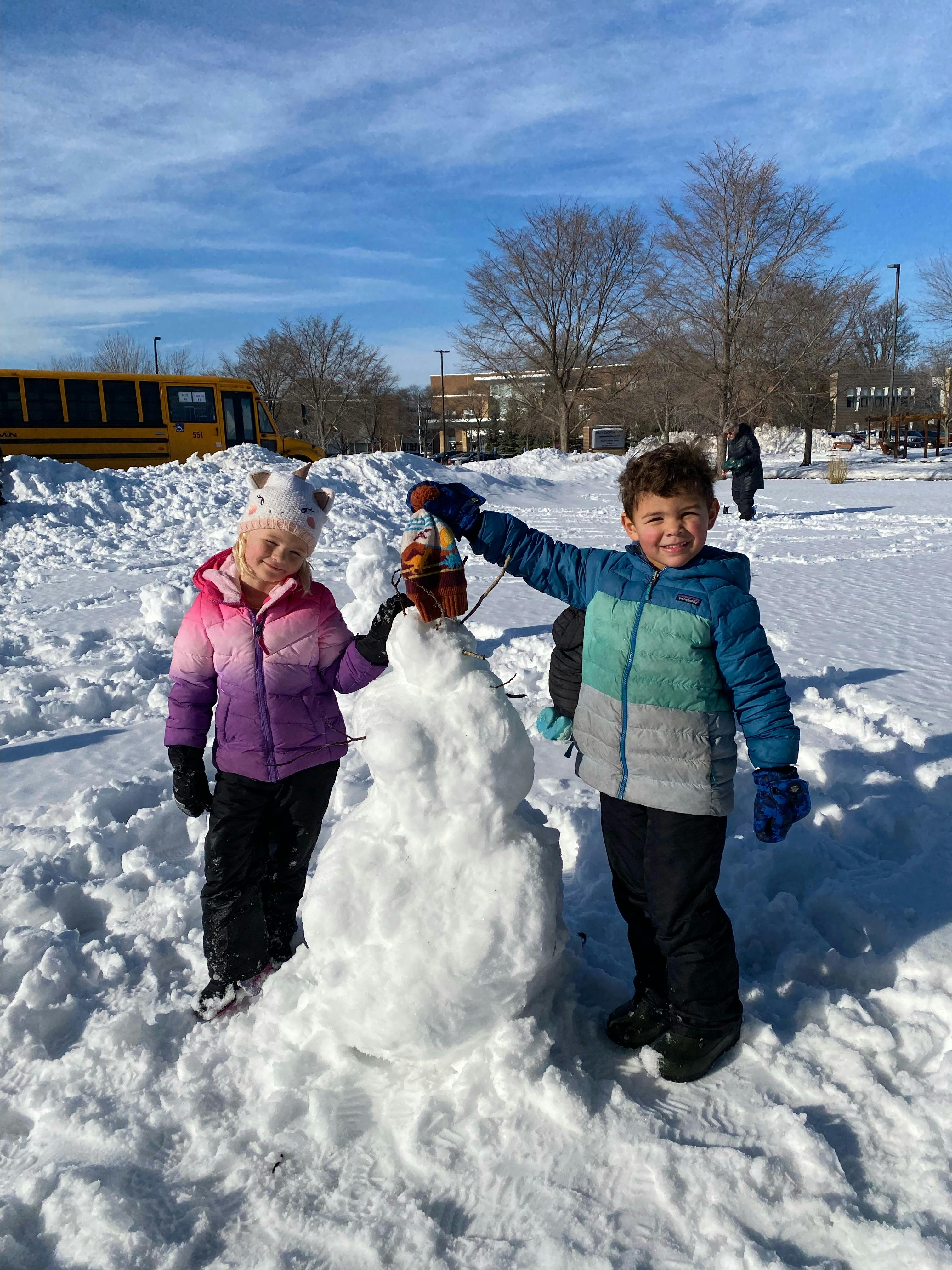 two children making a snowman in the snow