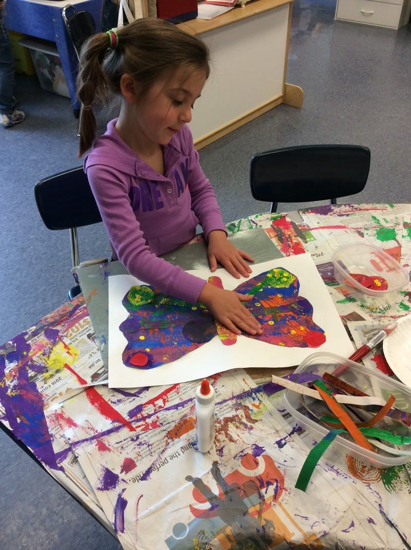 Child making a colorful butterfly craft in a classroom