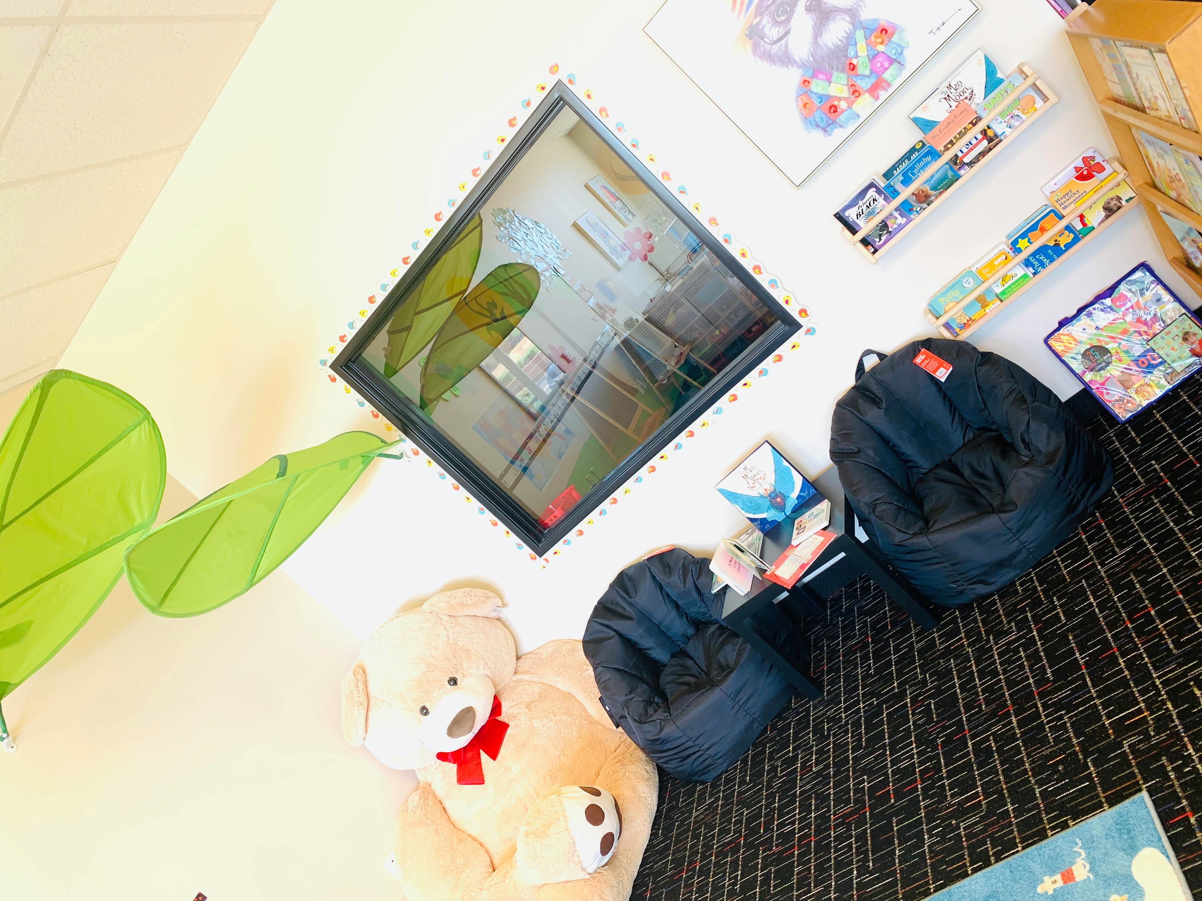 Teddy bear, beanbag chairs, and a window with green leaf decorations