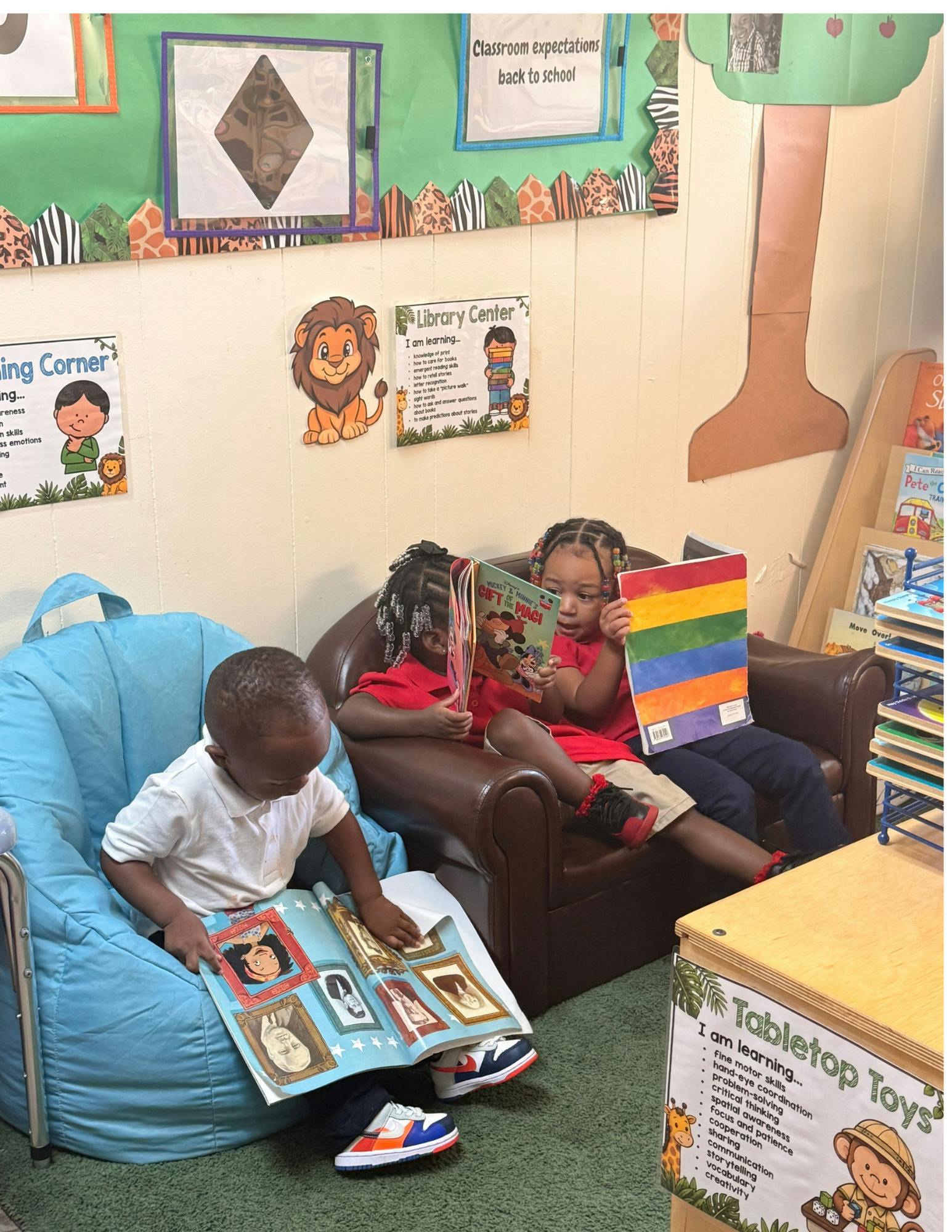 Three children reading books in a library center at school