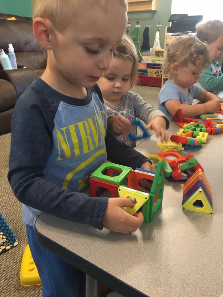 Child playing with colorful magnetic building blocks at a table