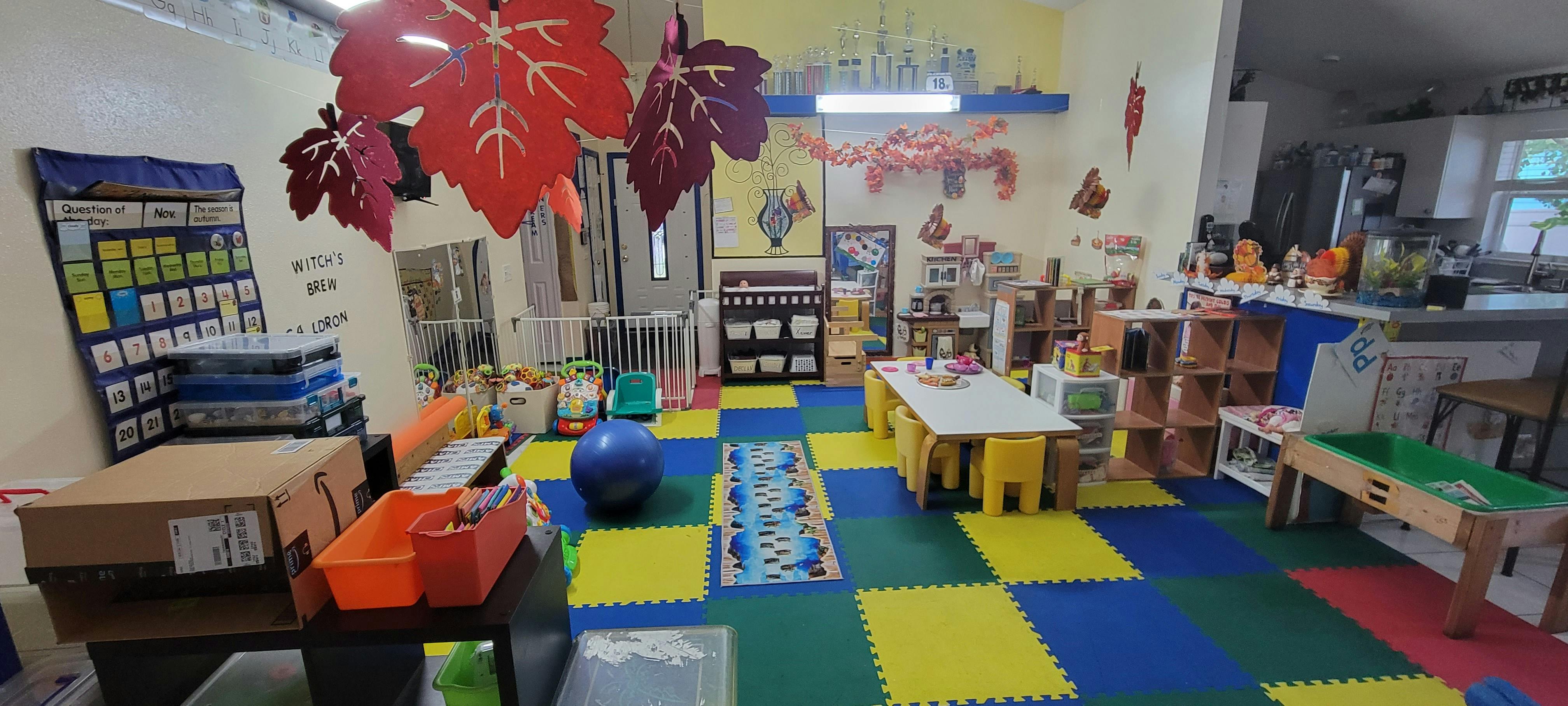 Playroom with colorful floor mats, small tables, and fall leaf decorations