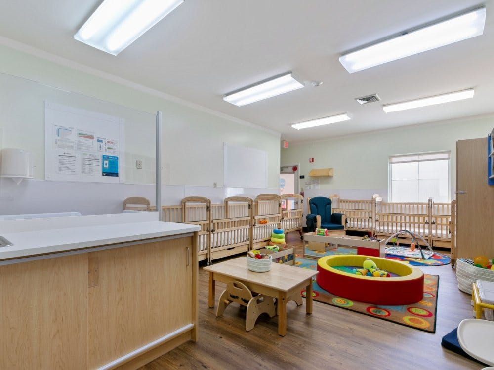 Cribs, playmats, and small tables in a childcare room
