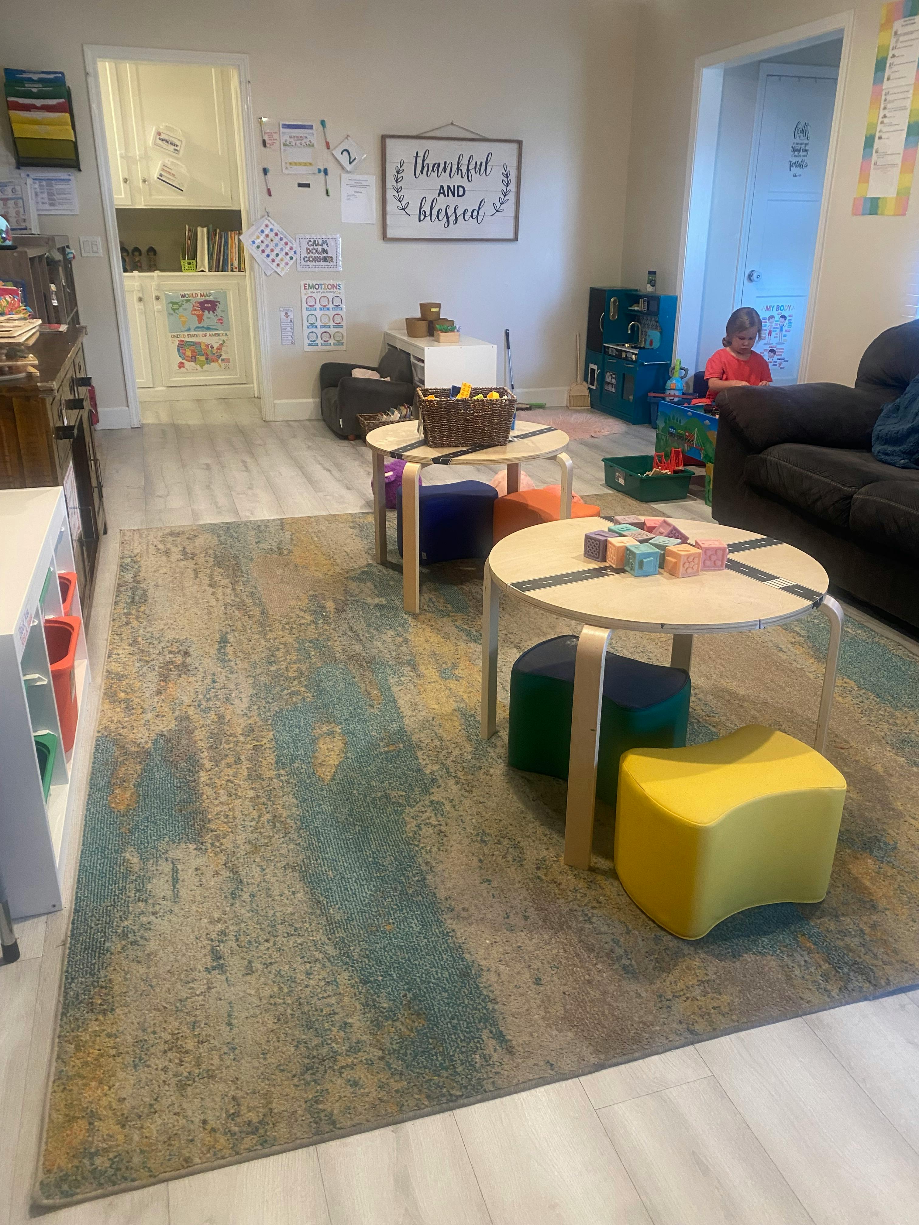 Child sitting on floor in a room with small tables and stools
